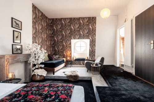 Chambre luxueuse à l'hôtel Henri II au Mans avec mobilier en velours noir, papier peint à motifs et vue sur jardin