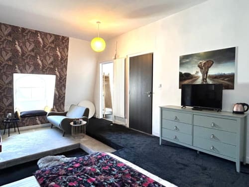 Chambre moderne de l'hôtel Henri II au Mans avec lit, TV, commode et vue sur tableau de jardin