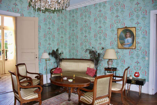 Élégant salon du Château de Vaux Morvan avec papier peint damassé turquoise, canapé rayé, fauteuils en bois et lustre