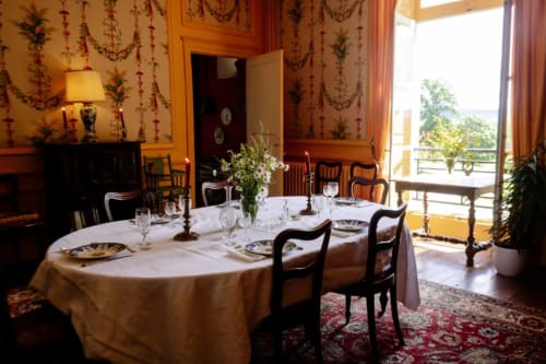 Elegant dining room at Château de Vaux Morvan with round table, period furniture, and botanical wallpaper, Étang sur Arroux