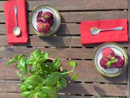 Présentation élégante de dessert dressé au Château de Vaux Morvan avec coulis rouge velouté, garniture de basilic frais et mise en place