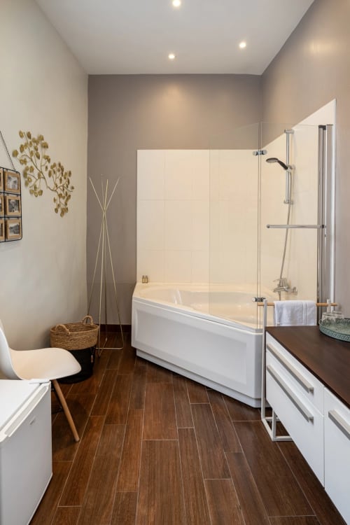 Salle de bains moderne de la suite Marquis à l'hôtel Henri II, Le Mans, avec baignoire ilôt, douche vitrée et finitions sombres