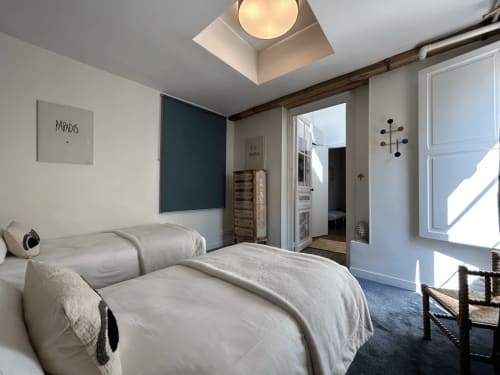 La suite Marquis de l'hôtel Henri II au Mans propose un lit queen-size aux draps crème, une lucarne, un mur d'accent bleu foncé et