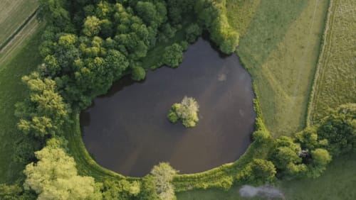 Aerial view of a serene pond surrounded by lush forests at Château de Vaux Morvan, a French bed and breakfast in Étang sur