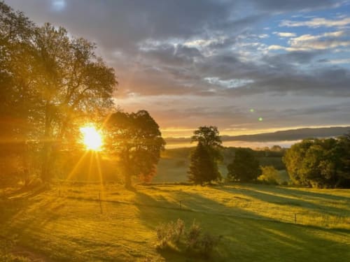 Coucher de soleil doré sur la campagne vallonnée du Château de Vaux Morvan, maison d'hôtes en Étang sur Arroux