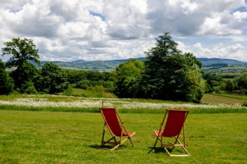 Deux chaises longues rouges sur pelouse verte face aux collines du Château de Vaux Morvan à Étang sur Arroux