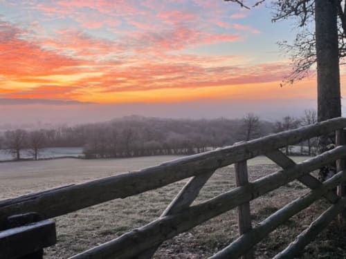 Sunrise over frosted fields at Château de Vaux Moryan, Étang sur Arroux, with wooden fence and bare trees by water