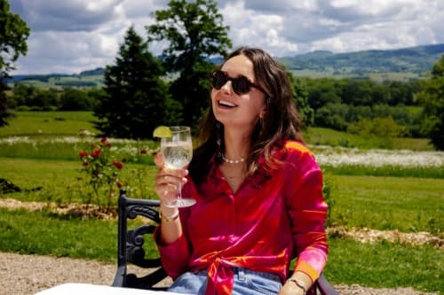 Femme en veste rouge dégustant du vin avec vue sur la campagne au Château de Vaux Morvan, Étang sur Arroux