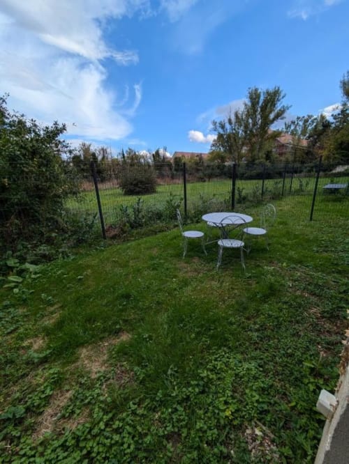 Peaceful garden seating area at Manoir Saint Joseph villa in Sens, France with wrought iron chairs and table