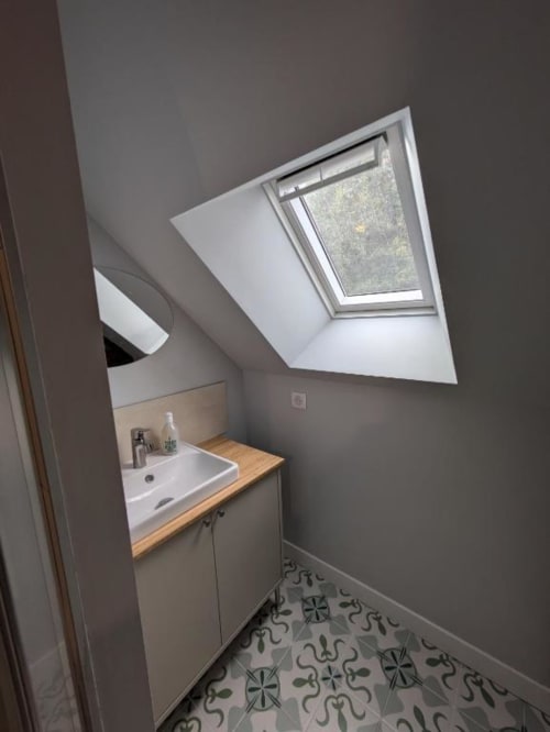 Salle de bain moderne avec puits de lumière au manoir Saint Joseph, lavabo sur plan de travail en bois et carrelage à motifs