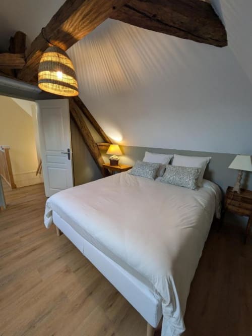 Cozy attic bedroom at Manoir Saint Joseph in Sens with queen bed, wooden beams, and warm lighting