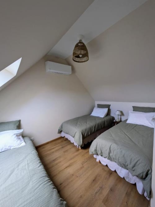 Attic bedroom at Manoir Saint Joseph with three beds, wooden floor, and woven pendant light