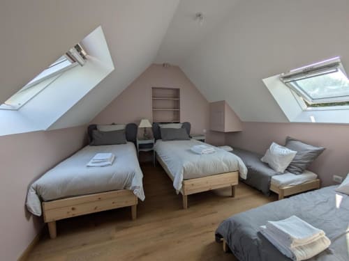 Bright attic bedroom at Manoir Saint Joseph with multiple beds, skylights, and wooden furnishings in Sens