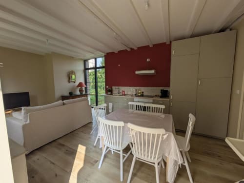 Open-plan dining and kitchen area at Manoir Saint Joseph, Sens with white exposed beams, red accent wall, and modern