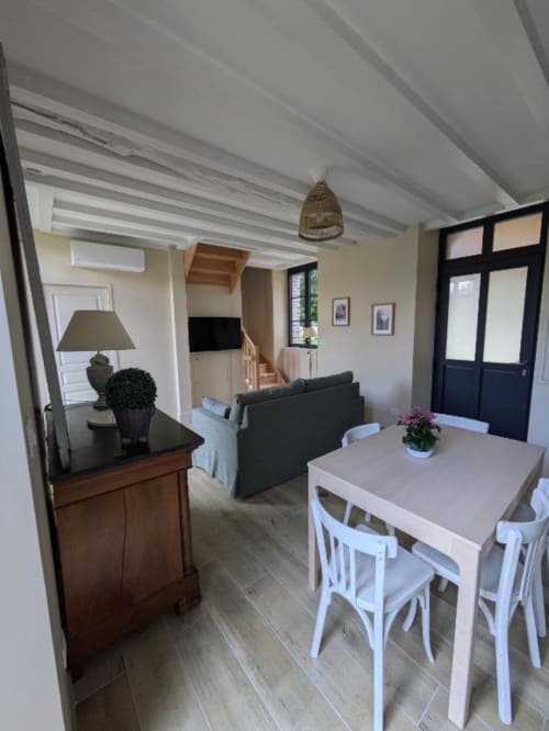 Séjour et salle à manger lumineux et ouvert à la villa Manoir Saint Joseph avec plafond à poutres blanches, table de salle à manger, canapé et