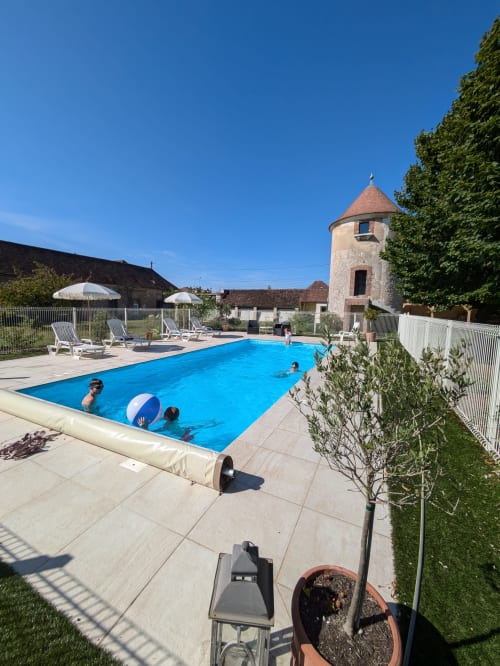 Piscine bleue éclatante au Manoir Saint Joseph à Sens, France, avec tour historique, transats et parasols