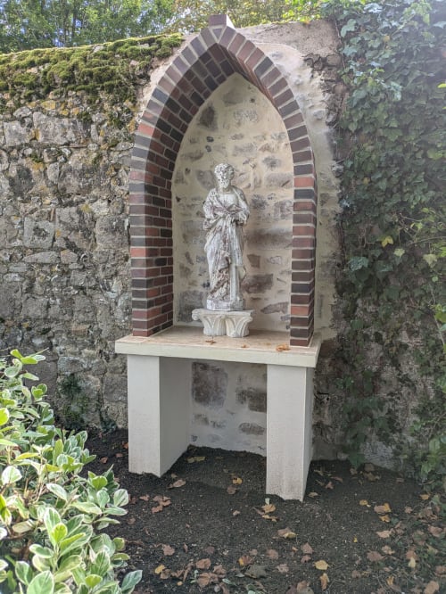 Niche de jardin en pierre avec voûte en briques abritant une statue classique sur piédestal au Manoir Saint Joseph à Sens