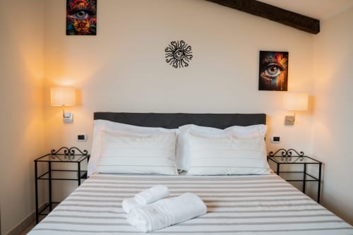 Camera moderna di Villa Del Sole Inn a Campobasso con letto queen, cuscini bianchi, biancheria a righe e illuminazione ambientale