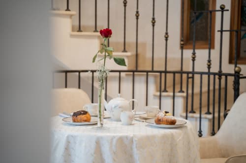 Elegante tavolo della colazione alla Villa Del Sole Inn con rosa rossa, pasticcini e teiera con vista sul cortile di Campobasso