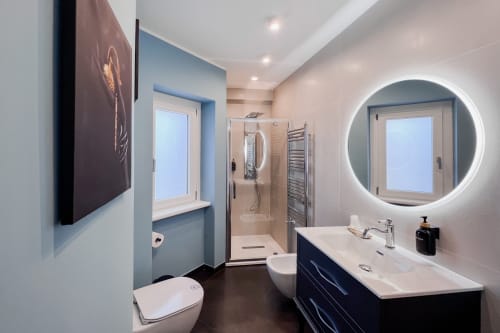 Bagno moderno a Villa Del Sole Inn Campobasso con specchio circolare illuminato, vanità scura e doccia walk-in