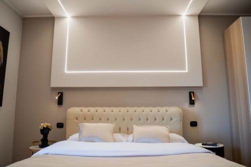 Camera moderna a Villa Del Sole Inn a Campobasso con testata capitonné crema, soffitto illuminato al neon e illuminazione contemporanea