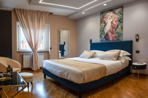 Camera moderna a Villa Del Sole Inn a Campobasso con letto upholstered blu, biancheria neutra e opere d'arte tropicale.