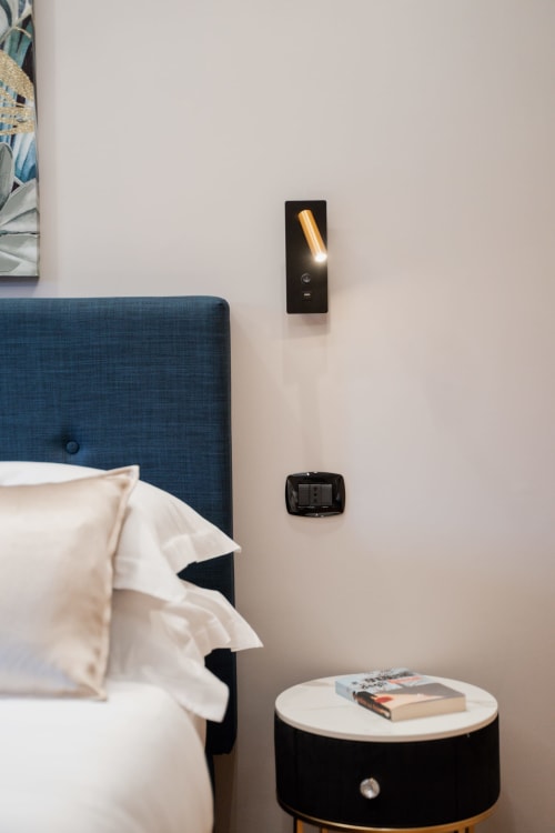 Camera moderna della Villa Del Sole Inn con testiera blu, applique murale, comodino e riviste a Campobasso