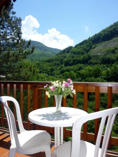 Vue sur les montagnes depuis le balcon de l'appartement La Rochetaillée à Brides-les-Bains avec table à manger et fleurs