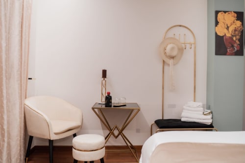 Camera elegante nella Villa Del Sole Inn di Campobasso con poltrona color crema, arredamento moderno e servizi spa