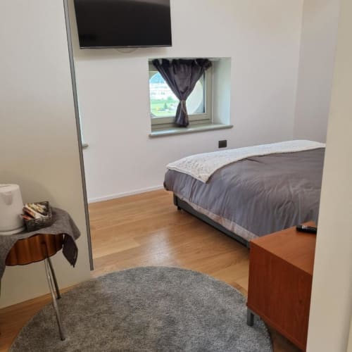 Camera moderna al Maso Kreuzberg B&B di Trento con letto, TV, finestra sulla campagna e pavimenti in legno