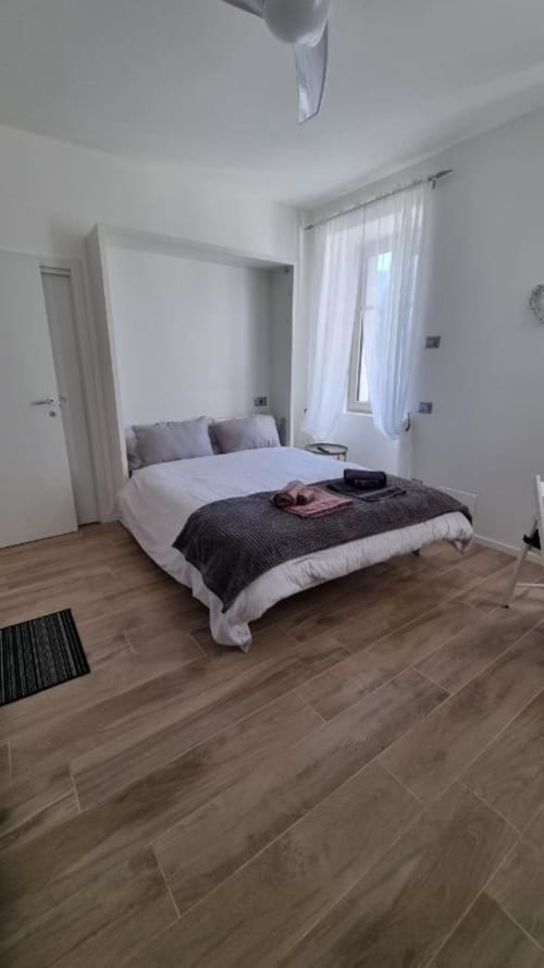 Camera moderna al Maso Kreuzberg B&B di Trento con letto a quattro colonne bianco, pavimenti in legno e ampia finestra con tende