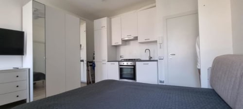 Cucina e camera da letto moderne presso il B&B Maso Kreuzberg a Trento, con mobili bianchi e letti scuri