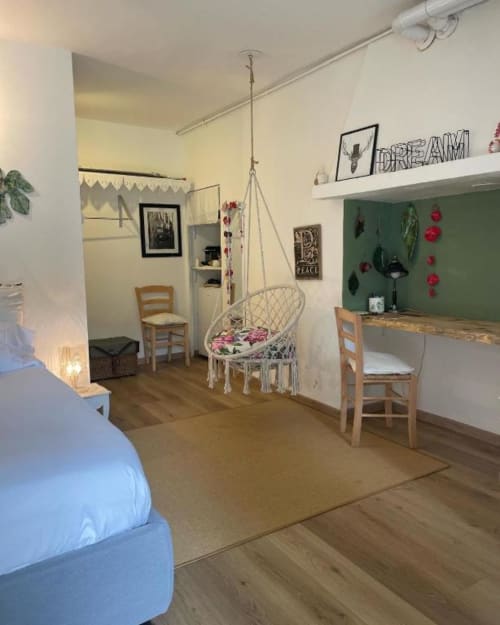 Wisteria Double Room at La Cascina di Bea B&B in Bergamo, Italy, featuring a bed, hanging chair, desk, and garden view