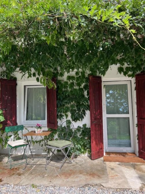 Garden patio entrance at La Cascina di Bea B&B in Bergamo, Italy, with ivy-covered white walls, red shutters, and outdoor