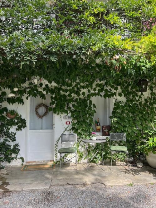 Lush ivy-covered entrance to Wisteria Double Room at La Cascina di Bea B&B in Bergamo, with white door and garden seating