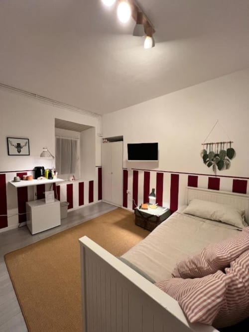 Dalia Room at La Cascina di Bea, Torre Boldone: modern bedroom with burgundy striped walls, bed, desk, TV, and garden view