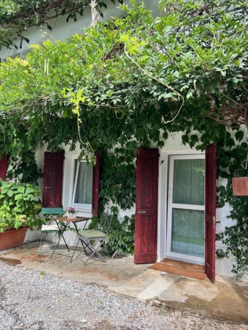 Dalia Room garden entrance at La Cascina di Bea, Bergamo - lush ivy-covered patio with red shutters and outdoor seating