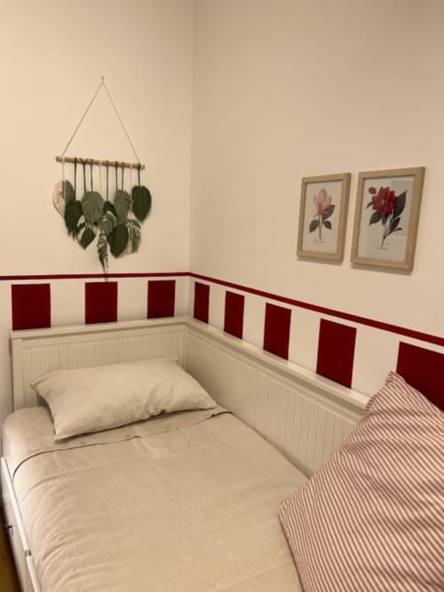 Cozy single bedroom at La Cascina di Bea B&B in Bergamo with cream bedding, red and white striped wall panels, and botanical