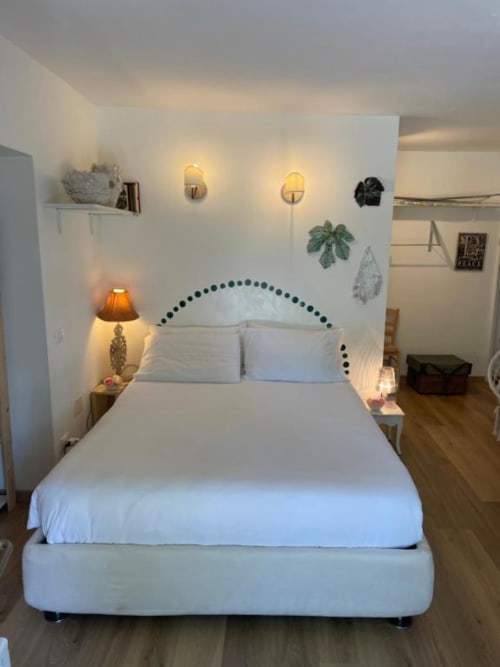 Bright bedroom at La Cascina di Bea with white upholstered bed, decorative headboard, plants, and warm lighting in Torre