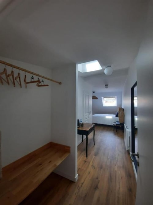 Couloir lumineux avec banc en bois et puits de lumière menant à la chambre de la Maison Rinette, Dijon