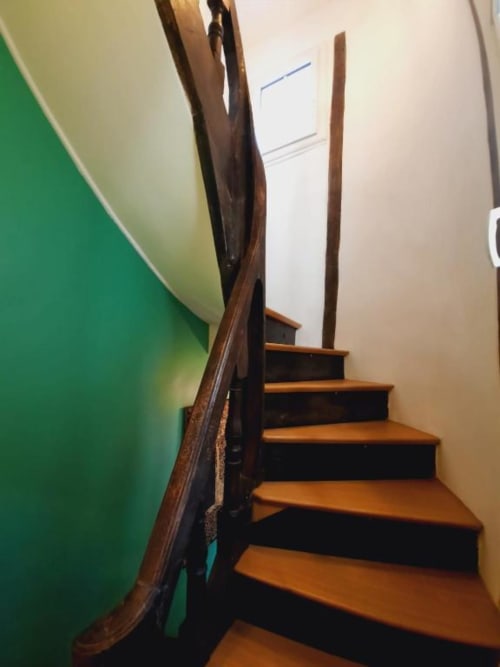 Escalier en bois et mur vert à la Maison Rinette B&B de Dijon, baigné de lumière naturelle