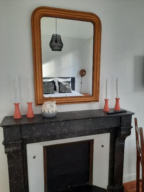 Élégante cheminée à Maison Rinette avec miroir en bois, chandeliers corail et figurine de hibou blanc