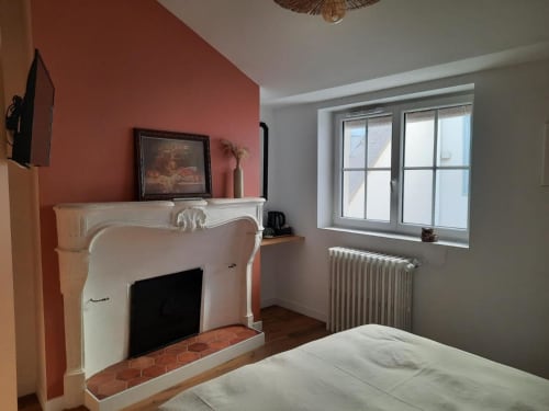 Chambre de la Maison Rinette B&B à Dijon avec cheminée, mur terracotta et grande fenêtre