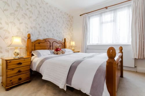 Deluxe Double Room at Brooklyn House Southgate with wooden bed, floral wallpaper, garden view windows, and bedside lamps