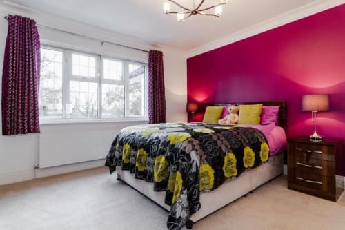 Superior King Room at Brooklyn House with vibrant magenta accent wall, yellow and black patterned bedding, and garden views