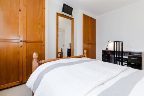 Deluxe Double Room at Brooklyn House B&B in Southgate, London with wooden wardrobe, white bedding and flat-screen TV