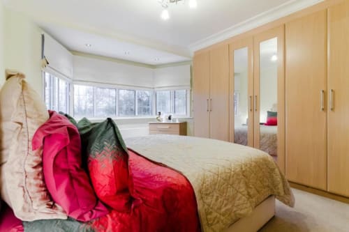 Spacious Deluxe King bedroom at Brooklyn House with wooden wardrobe, garden views, and red bedding