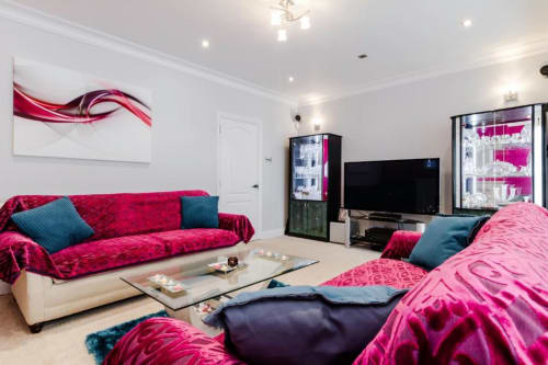 Luxurious King Room at Brooklyn House in Southgate with bold pink velvet sofa, matching bedding, flat-screen TV, and garden