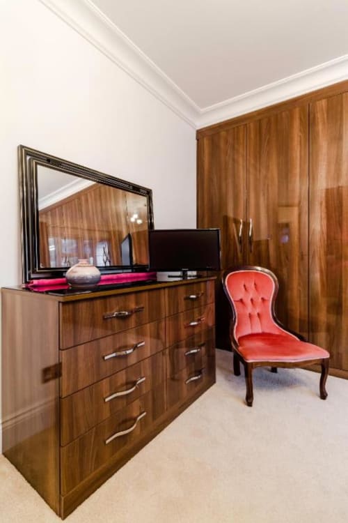 Superior King Room at Brooklyn House London with wooden furniture, flat-screen TV, red upholstered chair, and mirror