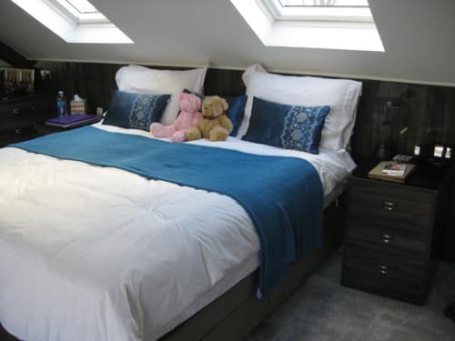 Deluxe Junior Suite bedroom at Brooklyn House, London, with white bedding, blue throw, patterned pillows, teddy bears, and